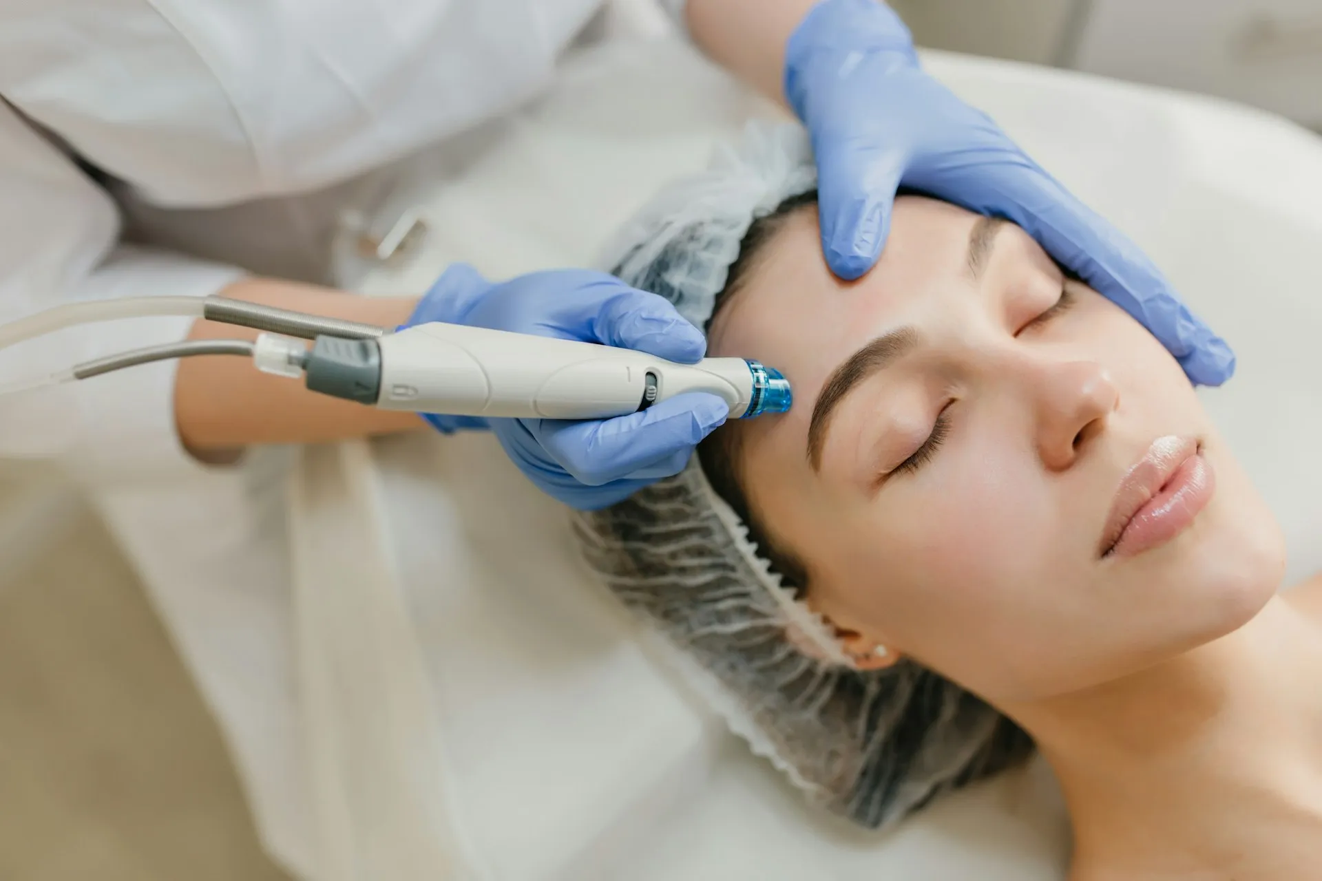 A practitioner performing a facial treatment with a handheld device