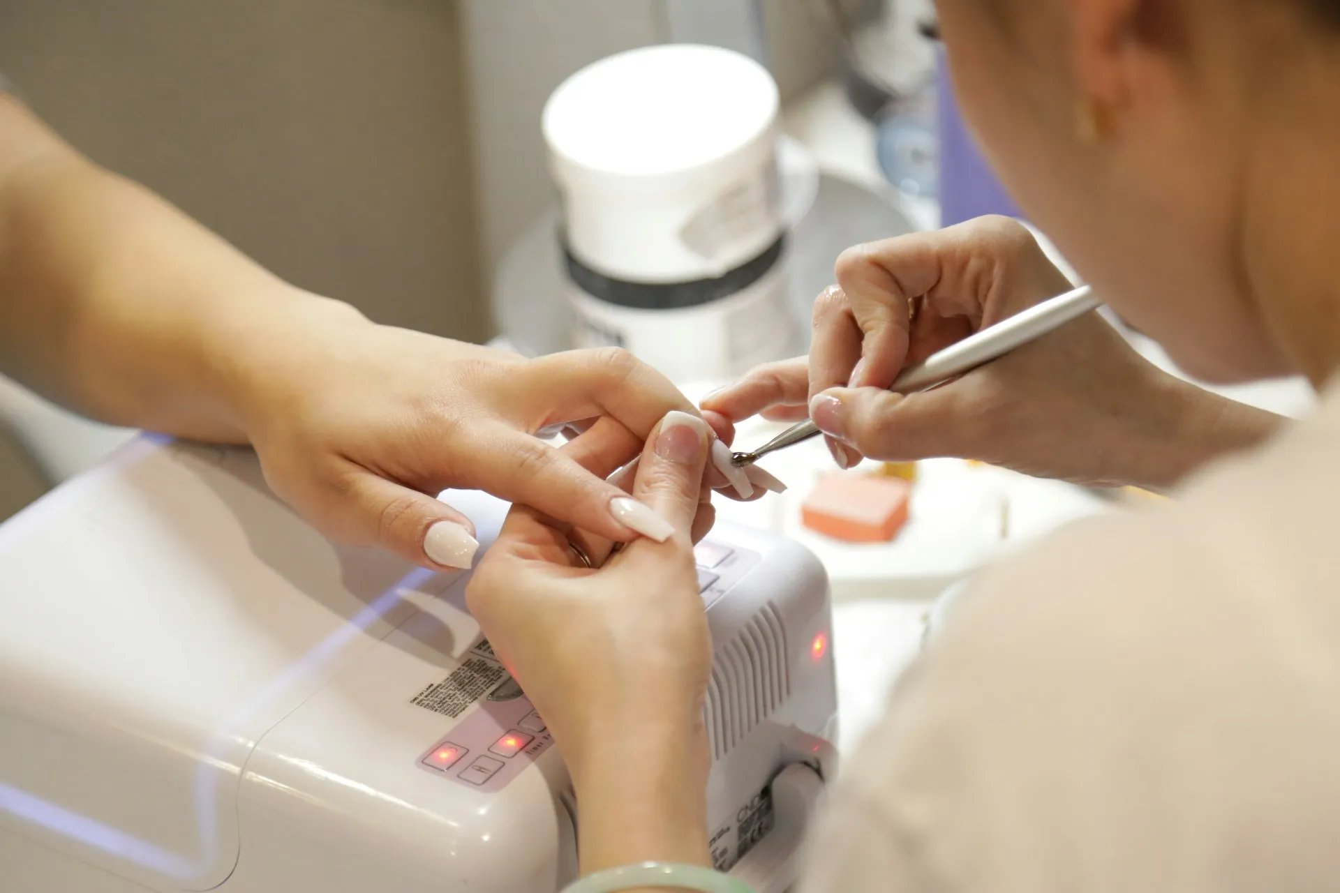 A nail technician working on a client’s manicure at a nail bar