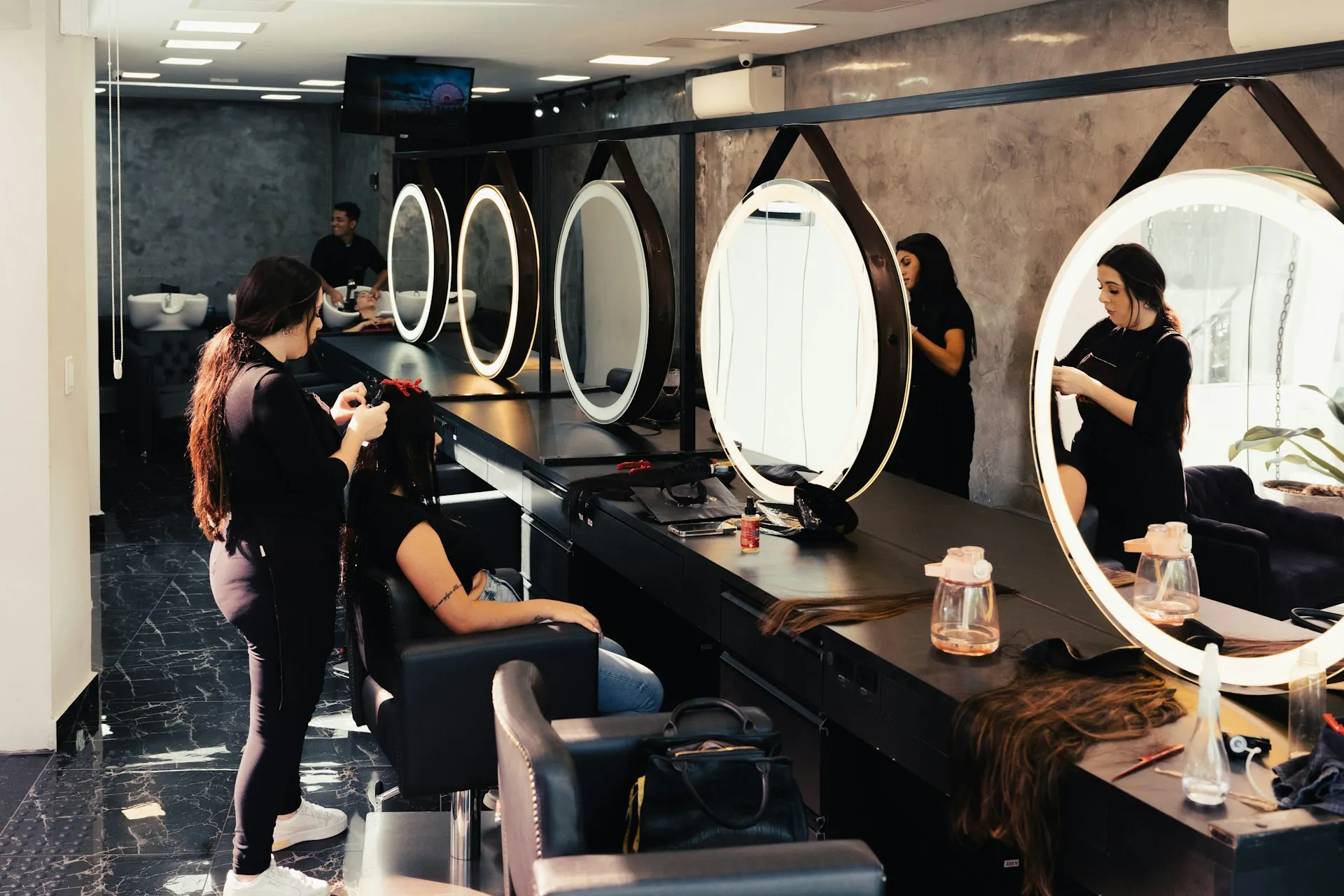 A stylist finishing a client’s hair at a salon station