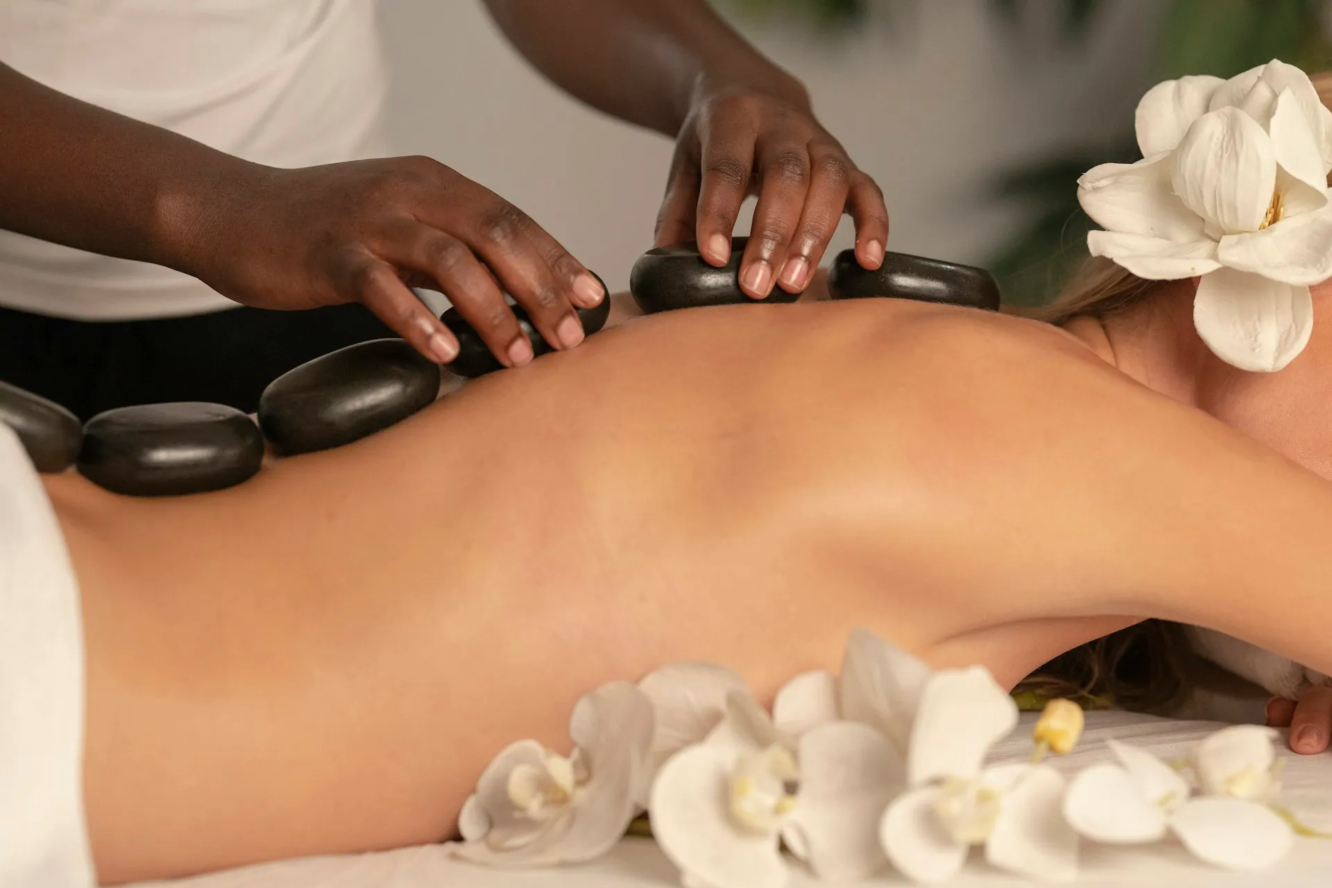 A client receiving a hot stone treatment on a spa table