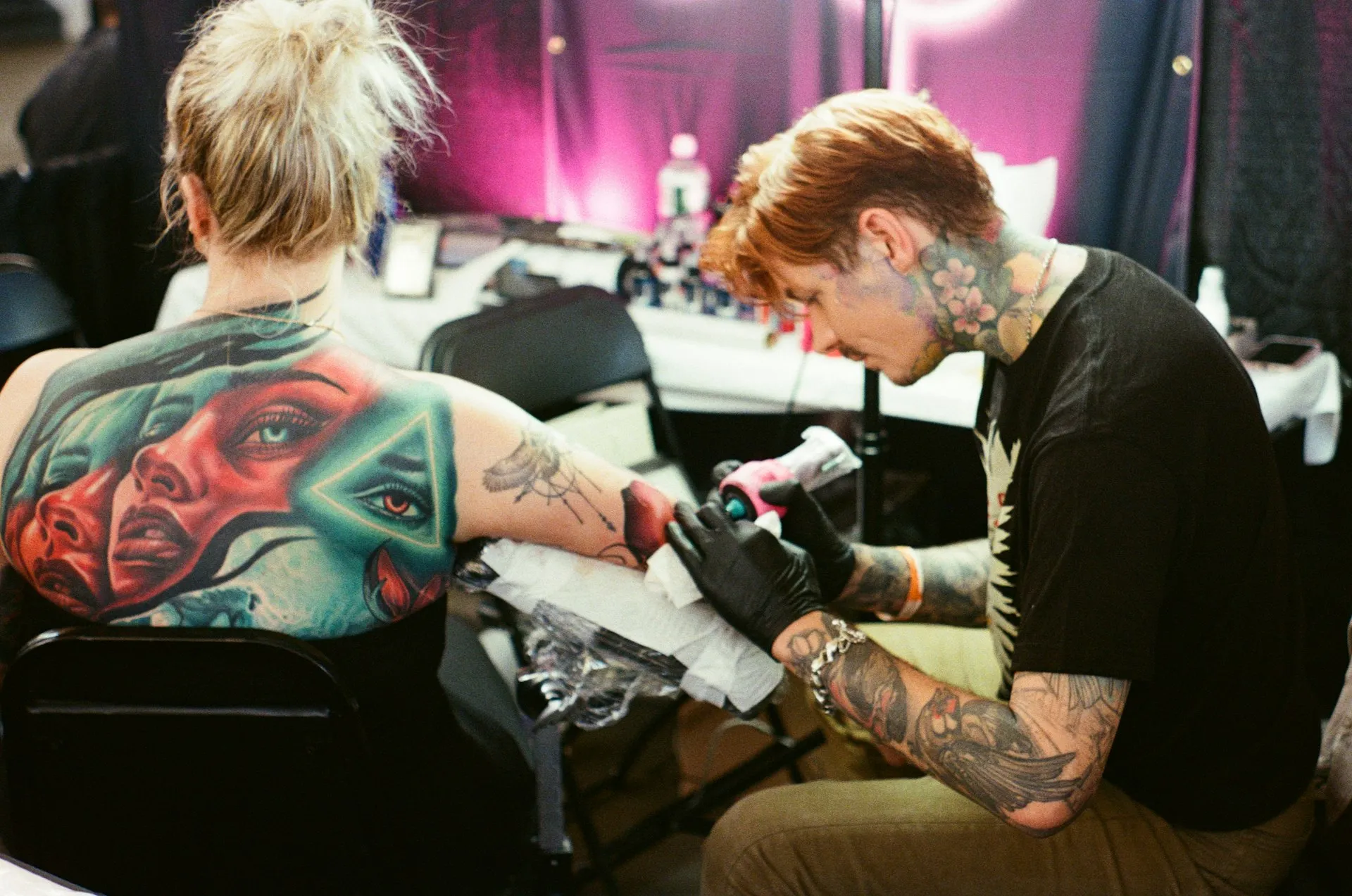 A tattoo artist working on a client’s arm in a studio